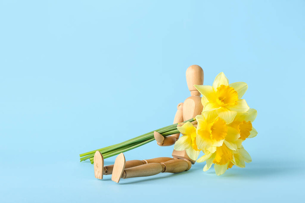 Wooden mannequin with beautiful daffodils on color background - Fotografie, Obrázek