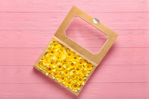 Box with beautiful daffodils on color wooden background - Photo, Image