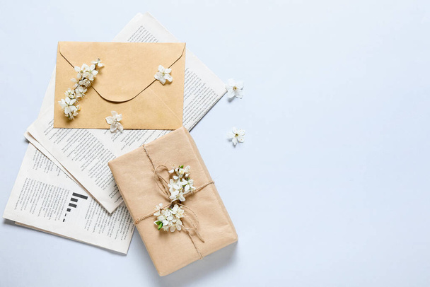 Beautiful blooming branches, gift box and newspaper on light background - Fotografie, Obrázek