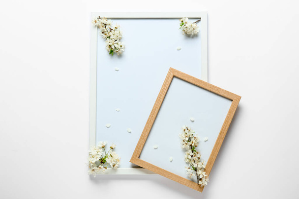 Blank frames and beautiful blooming branches on light background - Foto, afbeelding
