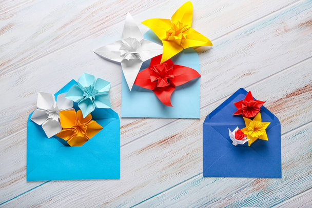 Origami narcissus with envelopes on white wooden background - Фото, изображение