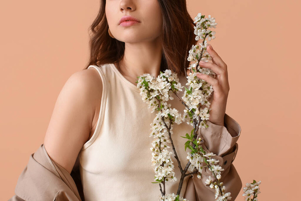 Schöne junge Frau mit blühenden Frühlingszweigen auf farbigem Hintergrund - Foto, Bild