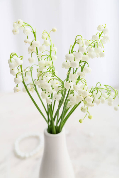 Vase with beautiful lily-of-the-valley flowers on light background - Photo, Image