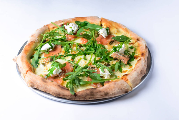 Pizza with mozzarella, salmon slices, fresh arugula. Isolated on white background. Italian cuisine concept, traditional pizza recipe. - Foto, Imagem