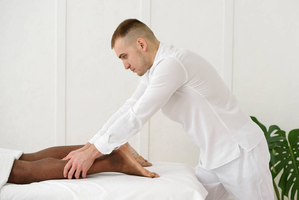 African american man having foot massage in spa, white background. Copy space, closeup - Fotografie, Obrázek