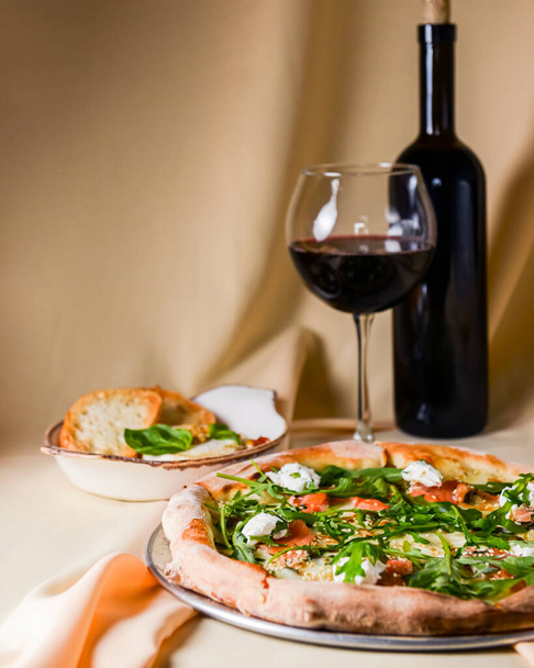Pizza with mozzarella, salmon slices, fresh arugula. Served with baked cheese camembert and red wine. Italian cuisine concept, traditional pizza recipe. - Fotografie, Obrázek