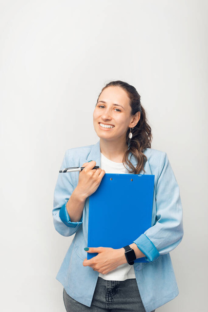 Retrato de jovem trabalhadora de escritório segurando papelada e sorrindo para a câmera. - Foto, Imagem