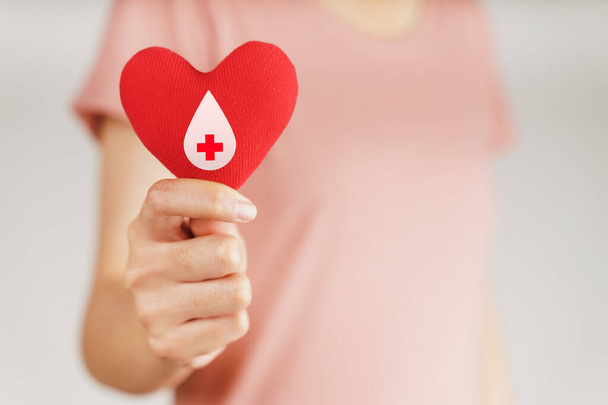 Frauenhände mit rotem Herz und Blutspenderzeichen. Gesundheitswesen, Medizin und Blutspende - Foto, Bild