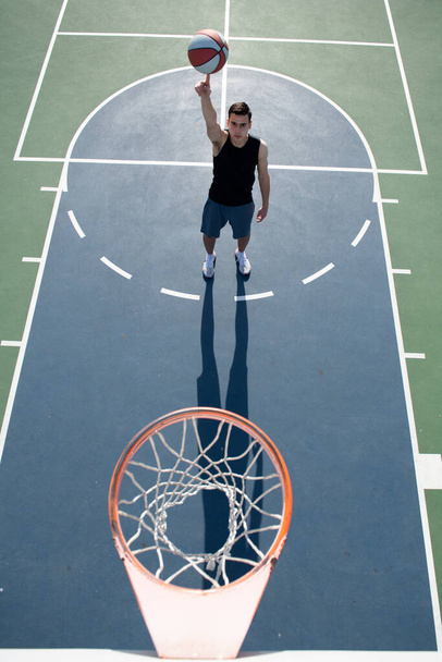 Action shot of young man playing basketball outdoors. Hand spinning basket ball. Balancing basketball on finger. - Foto, afbeelding