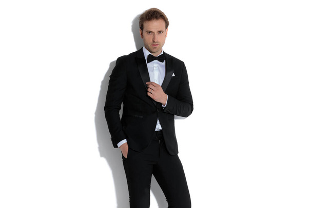 young businessman holding one hand in pocket and arranging his collar in a fashion pose - Photo, Image