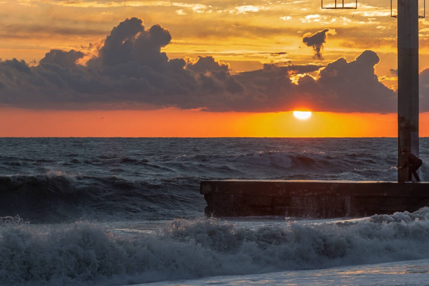 the sea at sunset, the red sun peeks out from behind the clouds. Adler. Sochi. Russia. - Photo, Image