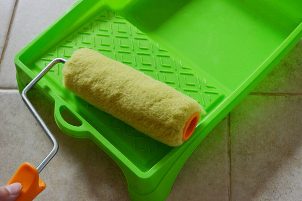 Paint roller in green plastic tray on ceramic tile background. - Photo, Image