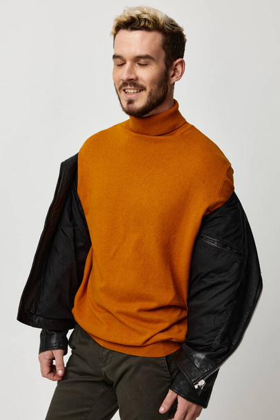 pohledný muž ve svetru a rozepnuté kožené bundy na světlém pozadí oříznutý pohled - Fotografie, Obrázek