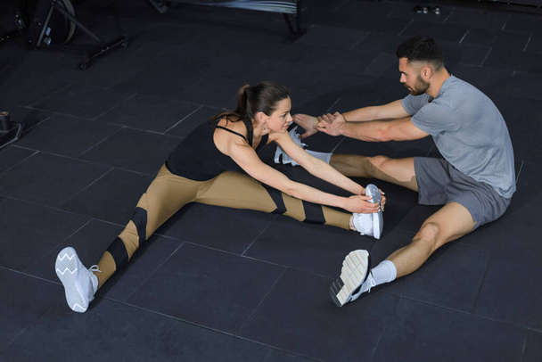 Portrait of a muscular couple doing leg stretchings - Foto, afbeelding