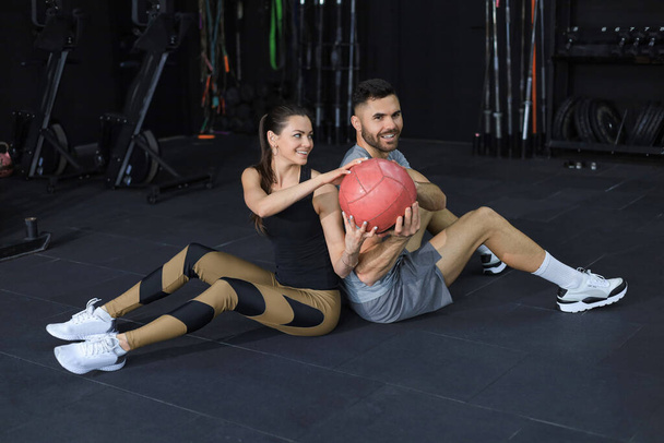 Apto e musculoso casal exercitando-se com bola medicina no ginásio - Foto, Imagem