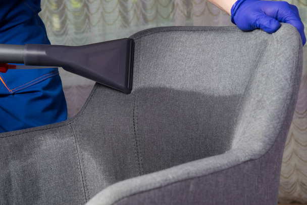 application of water with a cleaning solution for further cleaning of the gray chair, professional cleaning of upholstered furniture, large-scale plan - Photo, image