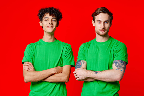 two men in green t-shirts are standing side by side communication - Foto, imagen