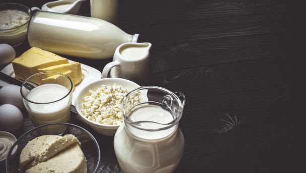 Σετ γαλακτοκομικών προϊόντων σε μαύρο ξύλινο φόντο, ποικιλία από γάλα, τυρί cottage, ξινή κρέμα και γιαούρτι, top view με αντίγραφο χώρο - Φωτογραφία, εικόνα