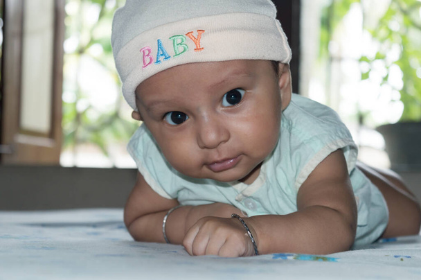 Aranyos baba emelő fej. Szoros portré. Boldog kisfiú néz és mosolyog a kamerába. Egészségügyi háttér. Édes kis csecsemőcske. Indiai etnikum. Fejlődési mérföldkő a baba számára. - Fotó, kép