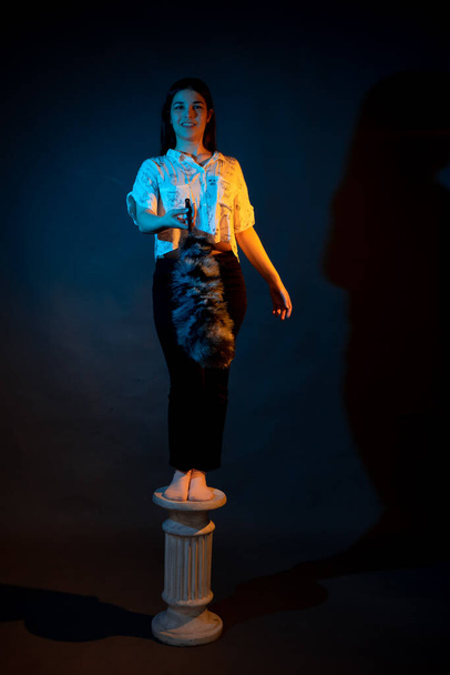 Girl on a stand on a dark background with multicolored light - Fotó, kép