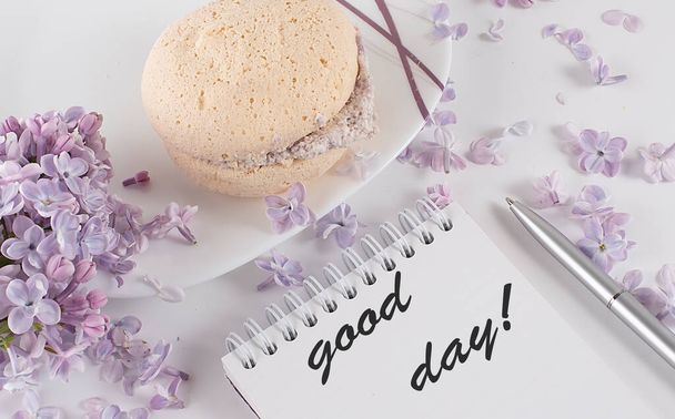an open notebook with and lilac flowers on desk and biscuits and text GOOD DAY - Photo, Image