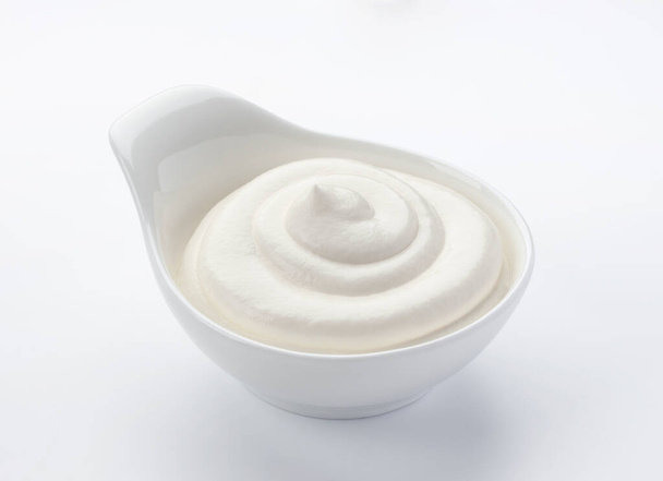 Crema agria en cuenco aislado sobre fondo blanco con camino de recorte - Foto, Imagen