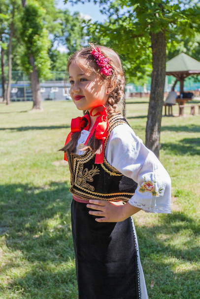Folklore serbio, linda y sonriente niña con ropa tradicional serbia. Retrato al aire libre, día de verano.  - Foto, Imagen