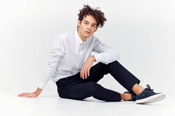 Tinédzser tornacipőben, fekete nadrágban és fehér ingben egy fényes szobában, teljes növekedésben. - Fotó, kép