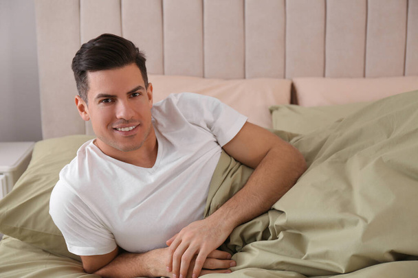 Man lying in comfortable bed with green linens - Foto, immagini