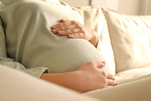 Pregnant young woman touching belly at home, closeup - Valokuva, kuva
