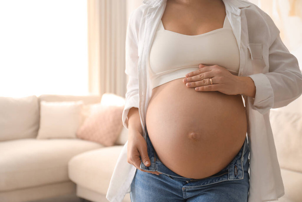 Pregnant young woman touching belly at home, closeup. Space for text - Foto, Bild
