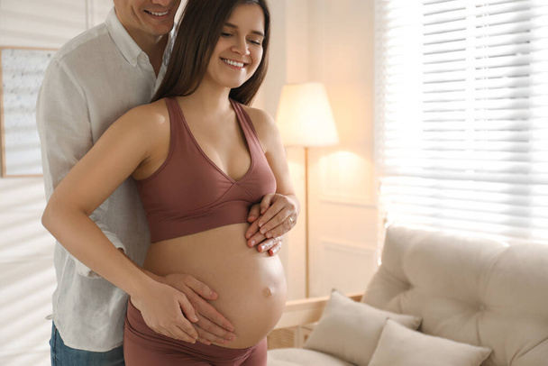 Man touching his pregnant wife's belly at home. Space for text - Foto, imagen