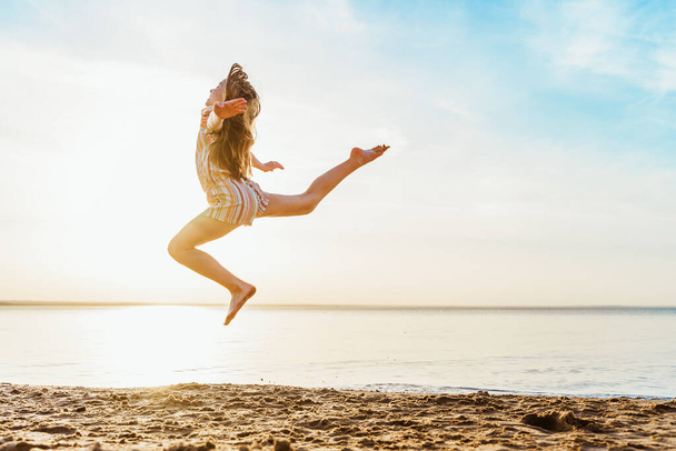 Meisje springen op het strand in het water, het concept van een leuke zomervakantie - Foto, afbeelding