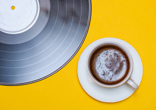 old vinyl record and coffee cup on yellow background  - Foto, afbeelding