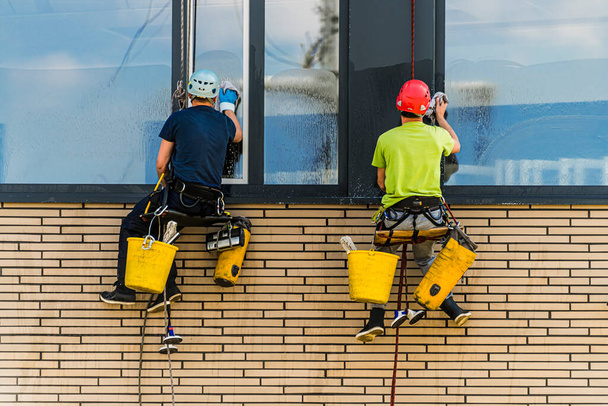 Dos hombres limpiando ventanas en un edificio de oficinas - Foto, Imagen