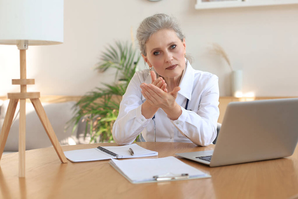 Older woman doctor therapist wearing headset video call talking to web camera consulting virtual patient online by video conference call chat. - Фото, зображення