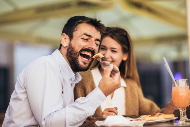 Hymyilevä pari treffeillä nauttimassa pizzaa ravintolassa yhdessä - Valokuva, kuva