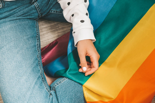 Closeup of young caucasian millennial hippie woman with painted rainbow flag in heart shape painted in wrist. Rainbow color tattoo, symbol of LGBT pride month - Foto, imagen