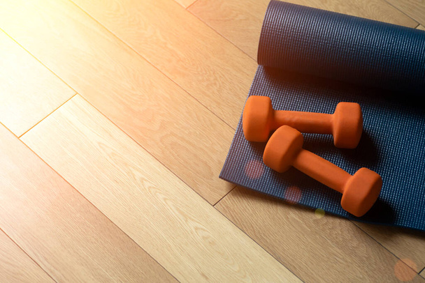 Yoga y fitness background. Parquet de piso de madera o laminado con alfombra y mancuernas para entrenar en una sala de yoga o gimnasio - Foto, Imagen