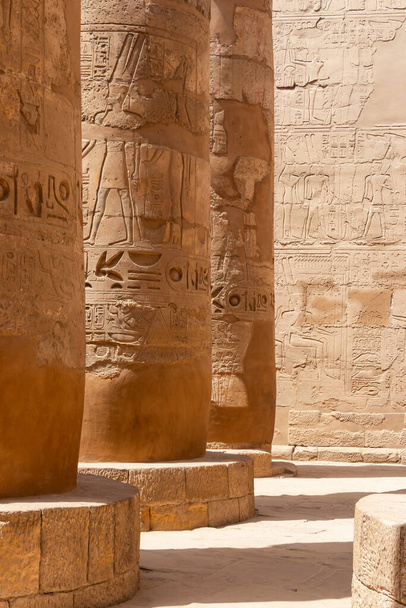 A fragment of several columns that are part of the large hypostyle hall of the Karnak temple complex, ancient hieroglyphs and inscriptions are visible on the columns - Photo, Image
