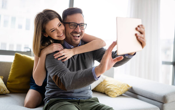 Young couple watching media content online in a tablet in the living room. - 写真・画像