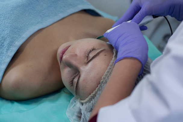 Cosmetological procedure microdermabrasion for a girl with problem skin. The beautician makes a treatment procedure to the patient. - Φωτογραφία, εικόνα