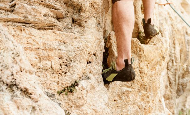 Un homme méconnaissable escalade une montagne. chaussures d'escalade détail. sports à risque et aventure. activités de montagne. - Photo, image