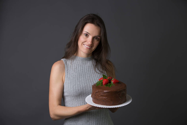 Middle age woman, celebrating her birthday with cake, isolated image on gray background - Zdjęcie, obraz