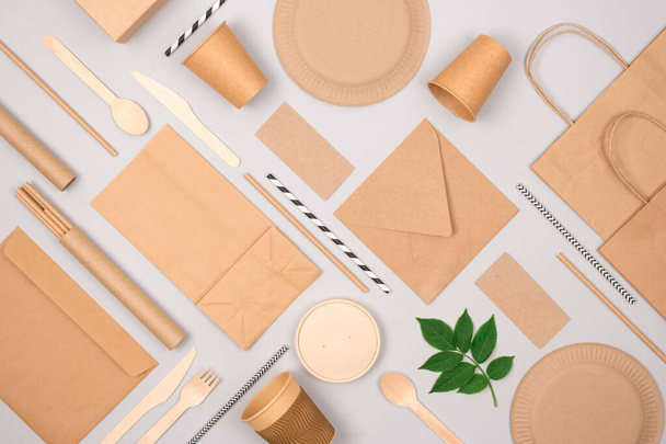 Set of eco-friendly tableware and kraft paper food packaging on light gray background. Street food paper packaging - cups, plates, straws, containers and paper bags. Mockup, flat lay. Selective focus - Photo, Image