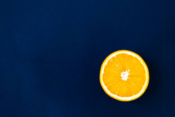 Top view of one orange round fruit on bright blue background. Rich citrus texture. Copy space. - Фото, изображение