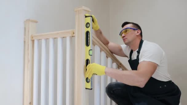 Inspecteur masculin de construction vérifier le niveau vertical des pièces d'escalier par niveau d'esprit, examen intérieur de l'escalier de la maison. Charpentier installe des escaliers dans une nouvelle maison moderne - Séquence, vidéo