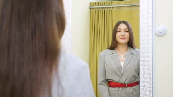 Mujer joven morena posa mirando el traje en el espejo - Imágenes, Vídeo