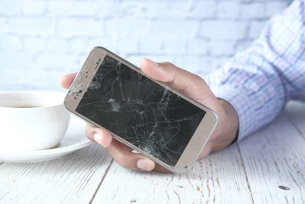 Detailní záběr muže ruka drží rozbitý chytrý telefon. - Fotografie, Obrázek