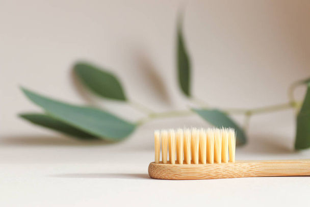 Eco-friendly bamboo toothbrush on a light beige background close-up. Oral hygiene and zero waste concept. Selective focus - 写真・画像